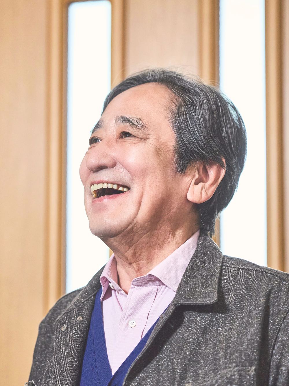 髙橋豊を演じるルー大柴。明るい窓辺で顔をほころばせて笑う。