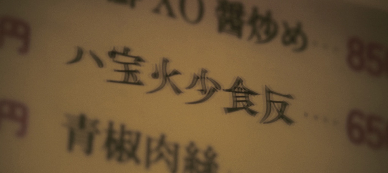 中華料理店のメニュー。漢字がにじんで、形がほどけて見える。